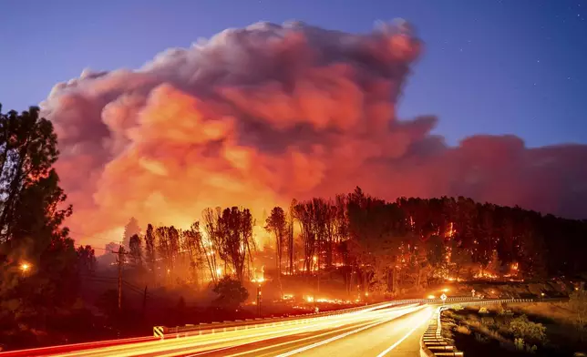 Seen in a long exposure photograph, the Park Fire burns along Highway 32 in the Forest Ranch community of Butte County, Calif., on Thursday, July 25, 2024. (AP Photo/Noah Berger)