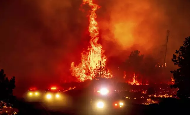 Flames leap above fire vehicles as the Park Fire jumps Highway 36 near Paynes Creek in Tehama County, Calif., Friday, July 26, 2024. (AP Photo/Noah Berger)