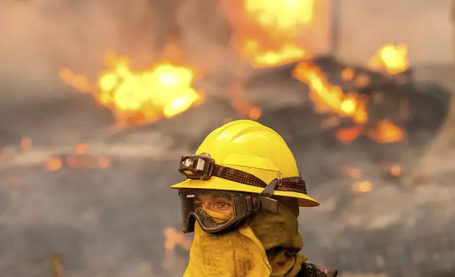 Firefighter Christian Moorhouse battles the Park Fire tears though the Cohasset community in Butte County, Calif., on Thursday, July 25, 2024. His crew was able to keep flames from reaching the mobile home they were protecting. (AP Photo/Noah Berger)