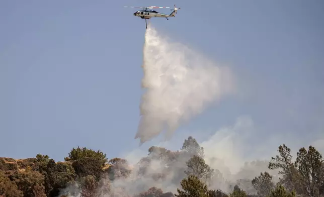 A Pacific Gas and Electric Company (PG&amp;E) firefighting helicopter releases water over a hot spot while battling the Thompson Fire, in Oroville, Calif., Wednesday, July 3, 2024. (Stephen Lam/San Francisco Chronicle via AP)
