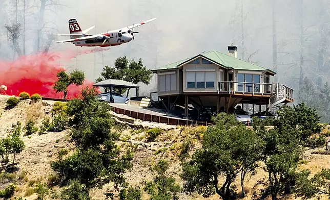 An air tanker drops retardant behind a home while battling the Toll Fire near Calistoga, Calif., on Tuesday, July 2, 2024. An extended heatwave blanketing Northern California has resulted in red flag fire warnings and power shutoffs. (AP Photo/Noah Berger)