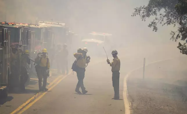 Fire crews walk through the smoke along Highway 32 as they battle the Park Fire near Forest Ranch, Calif., Sunday, July 28, 2024. (AP Photo/Nic Coury)