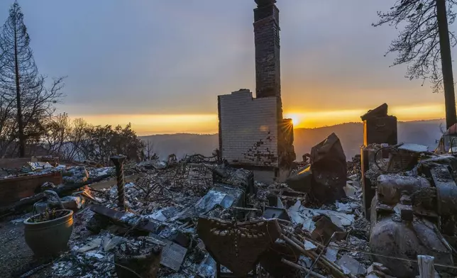 The sun sets over the remains of a house that was destroyed in the Park Fire near Forest Ranch, Calif., Saturday, July 27, 2024. (AP Photo/Nic Coury)