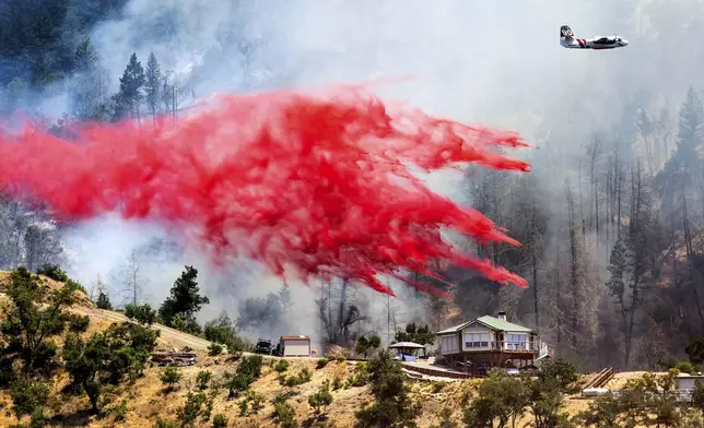 An air tanker drops retardant behind a home while battling the Toll Fire near Calistoga, Calif., Tuesday, July 2, 2024. An extended heatwave blanketing Northern California has resulted in red flag fire warnings and power shutoffs. (AP Photo/Noah Berger)