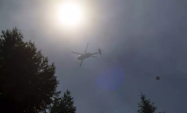 A helicopter carries waters over the Park Fire near Forest Ranch, Calif., Tuesday, July 30, 2024. (AP Photo/Nic Coury)