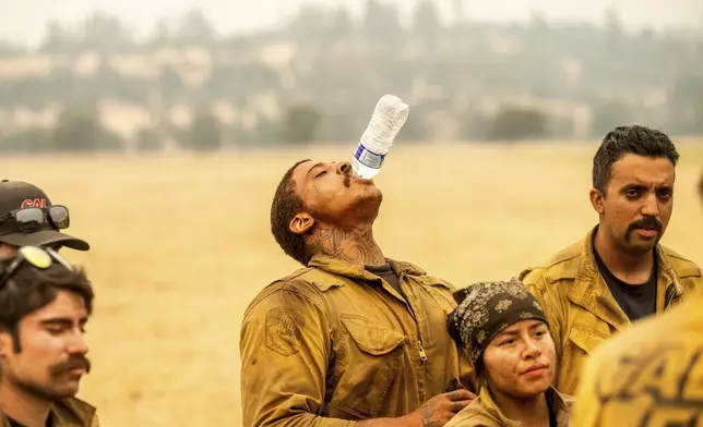 Firefighter Ismael Pugh chugs water during a briefing while battling the Park Fire in Tehama County, Calif., on Saturday, July 27, 2024. (AP Photo/Noah Berger)