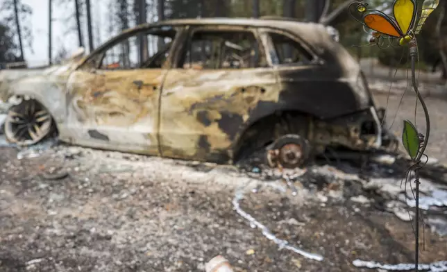 A lawn ornament stands in front of a burned car that was destroyed in the Park Fire near Forest Ranch, Calif., Saturday, July 27, 2024. (AP Photo/Nic Coury)