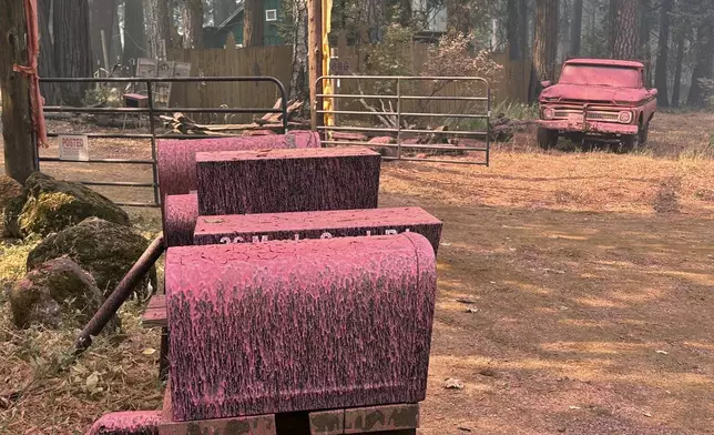 A vehicle and mailboxes are doused with retardant in the aftermath of the Park Fire, Sunday, July 28, 2024, in the Cohasset community of Butte County, Calif. (AP Photo/Eugene Garcia)