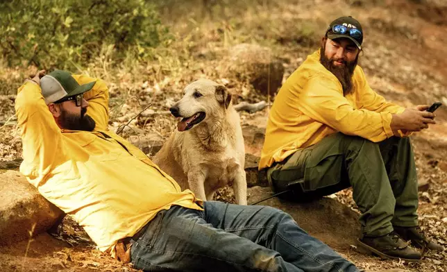 Water truck drivers Robert Cramer, left, and Daniel Rudkin, sit with a dog they found as the Park Fire tears through the Cohasset community in Butte County, Calif., on Thursday, July 25, 2024. (AP Photo/Noah Berger)