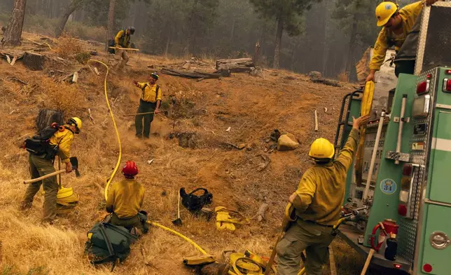 Firefighters with the United States Forest Service Lassen National Forest prepare a hoselay on a hillside during the Park fire near Paynes Creek in Tehama County, Calif., Saturday, July 27, 2024. (Stephen Lam/San Francisco Chronicle via AP)