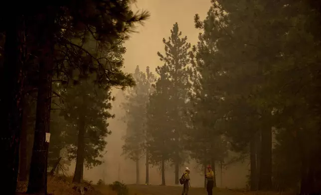 CTwo U.S. Forest Service firefighters confer on the Park Fire as smoke fills the air near Paynes Creek (Tehama County) on Saturday, July 27, 2024. (Stephen Lam/San Francisco Chronicle via AP)