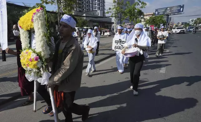 Environmental activists march on a main street as they head to Phnom Penh Municipality Court, in Phnom Penh, Cambodia, Tuesday, July 2, 2024. Ten members of a nonviolent environmental activist group in Cambodia were convicted on Tuesday on charges of conspiracy to commit a crime, receiving prison sentences of six years each. The words in a flower frame is read "Justice". (AP Photo/Heng Sinith)