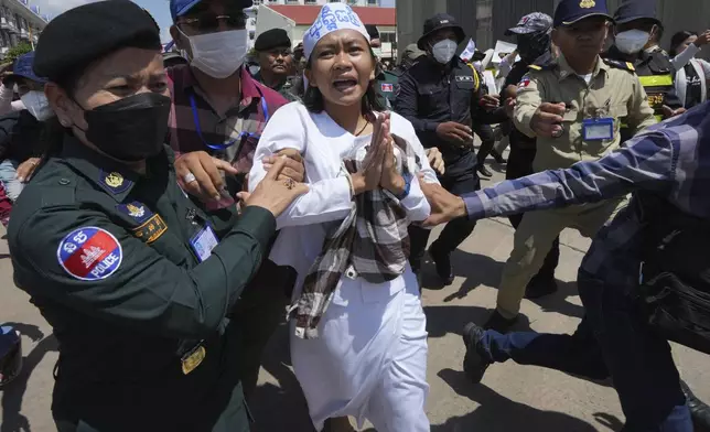 An environmental activist, center, is escorted by polices personnel near Phnom Penh Municipality Court, in Phnom Penh, Cambodia, Tuesday, July 2, 2024. Ten members of a nonviolent environmental activist group in Cambodia were convicted on Tuesday on charges of conspiracy to commit a crime, receiving prison sentences of six years each. (AP Photo/Heng Sinith)