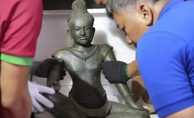Cambodian museum staff members place an artifact statue as it returned from U.S to Cambodia, before an official ceremony at the Cambodian National Museum in Phnom Penh Cambodia, Thursday, July 4, 2024. Cambodia on Thursday officially organized a welcome ceremony for the arrival of more than a dozen rare Angkor era sculptures from New York's Metropolitan Museum of Art that were tied to an art dealer and collector accused of running a huge antiquities trafficking network out of Southeast Asia. (AP Photo/Heng Sinith)