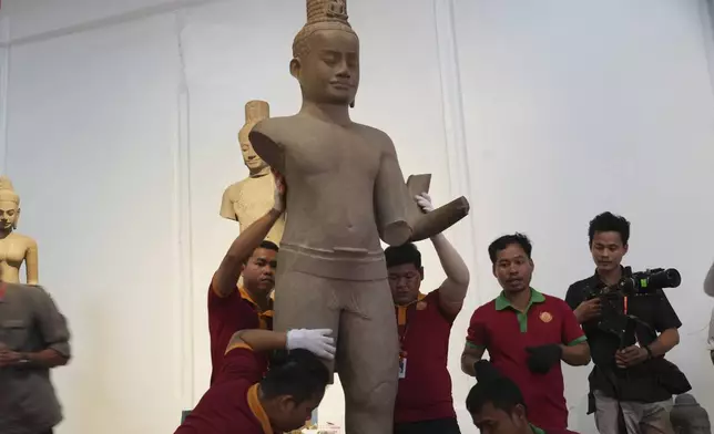 Museum staff members place an artifact as it returned from U.S to Cambodia, before an official ceremony at the Cambodian National Museum in Phnom Penh Cambodia, Thursday, July 4, 2024. Cambodia on Thursday officially organized a welcome ceremony for the arrival of more than a dozen rare Angkor era sculptures from New York's Metropolitan Museum of Art that were tied to an art dealer and collector accused of running a huge antiquities trafficking network out of Southeast Asia. (AP Photo/Heng Sinith)