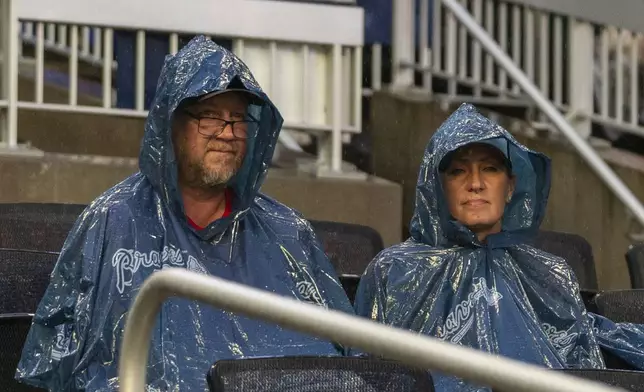 Baseball fans wait for the rain to pass before a baseball game between the St. Louis Cardinals and Atlanta Braves, Friday, July 19, 2024, in Atlanta. (AP Photo/Jason Allen)