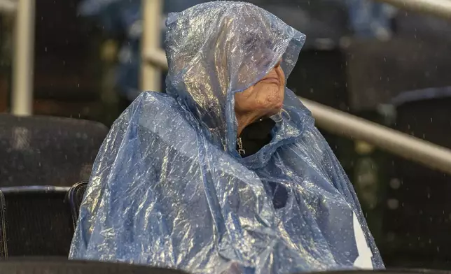 A baseball fan waits for the rain to pass during a rain delay before a baseball game between the St. Louis Cardinals and Atlanta Braves, Friday, July 19, 2024, in Atlanta. (AP Photo/Jason Allen)