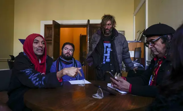 Chilean homeless transgender women Moka Valdes, left, and Paris Lopez, standing center, meet with a member of a city councilperson's staff, second from left, and a trans activist Victor Hugo Robles about how they are treated by police when they use public spaces in Santiago, Chile, Monday, April 29, 2024. Lopez said police confiscate her tent and blankets, as well as her HIV medication, while she sleeps in public spaces, and Valdes said she became homeless the previous year after losing her job. (AP Photo/Esteban Felix)