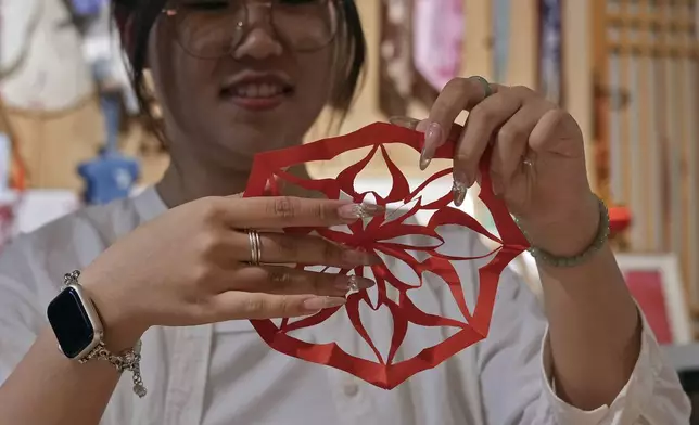 A university student shows a "nüshu" calligraphy paper cutting, at Xu Yan's Third Day Letter studio in Beijing on July 11, 2024. Nüshu is a centuries-old secret script. (AP Photo/Andy Wong)