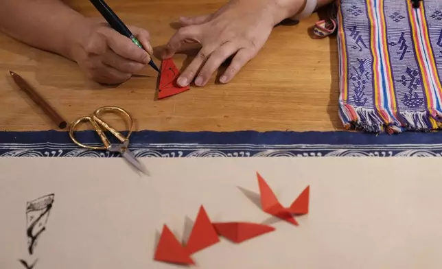 Xu Yan, an author of a textbook on nüshu, a centuries-old secret script, writes nüshu on paper cuttings at her studio in Beijing on July 11, 2024. (AP Photo/Andy Wong)