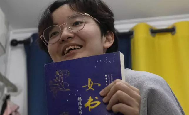 Lu Sirui, a 24-year-old working as a marketer, holds up a book with the word for nüshu, a centuries-old secret script, during an interview in Beijing, March 18, 2024. (AP Photo/Olivia Zhang)