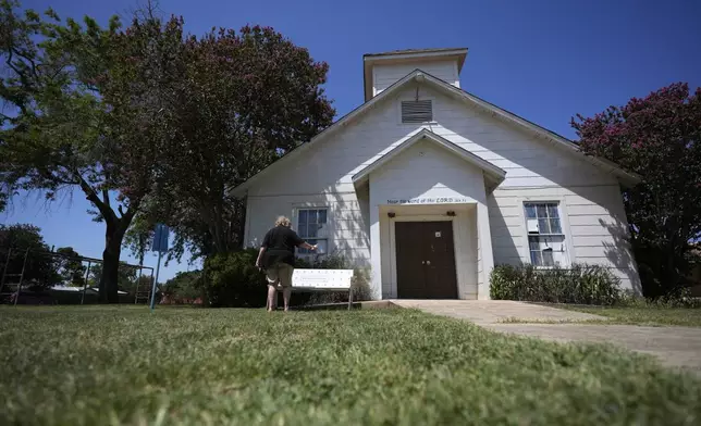 Karen Johns visits the First Baptist Church in Sutherland Springs, Texas, Tuesday, July 2, 2024, which is now a memorial to the 26 people who were killed by a gunman in 2017. The 100-year-old building has served as a memorial since the shooting, but now some want to raze the building. (AP Photo/Eric Gay)