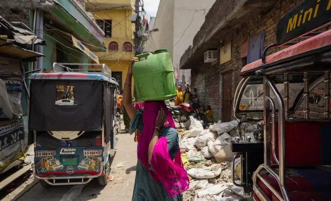 FILE - A woman walks carrying water collected from a public tap in a shanty town on the outskirts of Jammu, India, Tuesday, June 18, 2024. The official number of heat deaths listed in government reports barely scratches the surface of the true toll and that's affecting future preparations for similar swelters, according to public health experts. (AP Photo/Channi Anand, File)