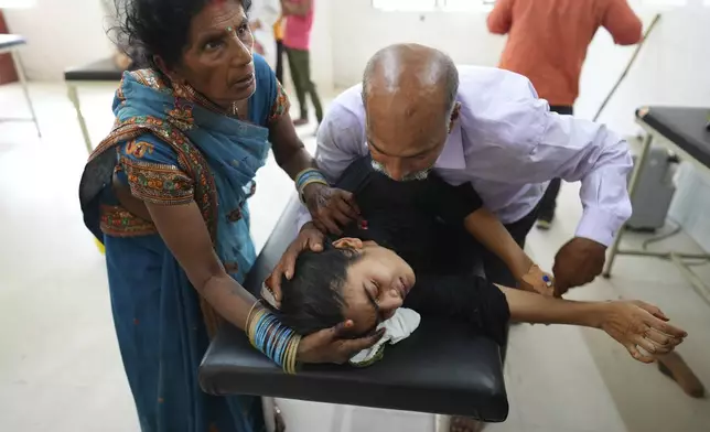 FILE - A father tries to calm his daughter suffering from a heat-related ailment as she is brought to the government district hospital in Ballia, Uttar Pradesh state, India, June 19, 2023. The official number of heat deaths listed in government reports barely scratches the surface of the true toll and that's affecting future preparations for similar swelters, according to public health experts. (AP Photo/Rajesh Kumar Singh, File)
