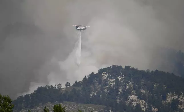 A helicopter drops water on the Alexander Mountain fire Tuesday, July 30, 2024, west of Loveland, Colo. (Zachary Spindler-Krage/The Denver Post via AP)