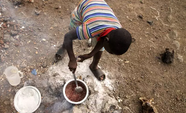 A boy cooks red beans for his little brothers at a refugee camp on the outskirts of Goma, Democratic Republic of the Congo, Thursday, July 11, 2024. The top U.N. official in Congo on Monday welcomed a two-week humanitarian cease-fire in its mineral-rich east, where she said violence has reached "alarming levels" and risked provoking a wider regional conflict. (AP Photo/Moses Sawasawa)