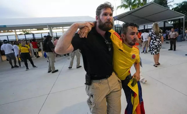 A security agent assist a fan who was waiting to enter the stadium prior to the Copa America final soccer match between Argentina and Colombia, in Miami Gardens, Fla., Sunday, July 14, 2024. (AP Photo/Lynne Sladky)