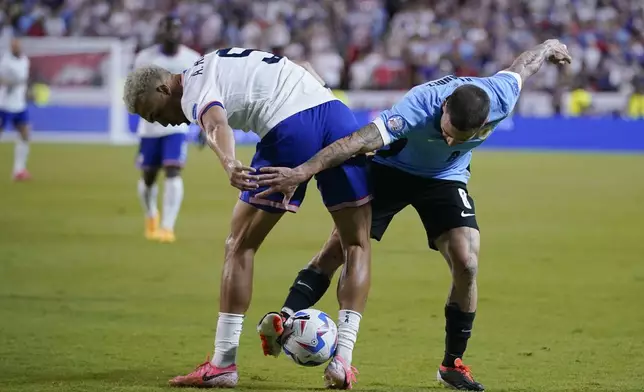 Antonee Robinson, left, of the United States, and Uruguay's Nahitan Nandez, right, battle for the ball during a Copa America Group C soccer match, Monday, July 1, 2024, in Kansas City, Mo. (AP Photo/Ed Zurga)