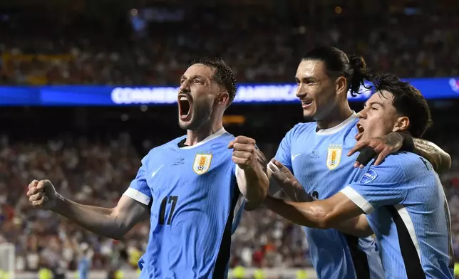 Uruguay's Matias Vina, left, celebrates his side's opening goal against United States scored by teammate Mathias Olivera during a Copa America Group C soccer match in Kansas City, Mo., Monday, July 1, 2024. (AP Photo/Reed Hoffman)