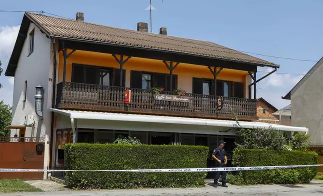 A police officer stands outside the cafe where the shooter was arrested, in Daruvar, central Croatia, Monday, July 22, 2024. An armed assailant entered a care home for older people in central Croatia Monday and opened fire, killing five people and wounding several others, authorities and media reports said. (Zeljko Puhovski/Cropix via AP)