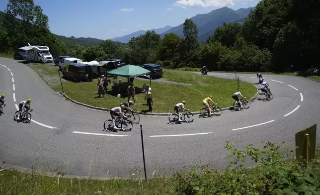 Slovenia's Tadej Pogacar, wearing the overall leader's yellow jersey, follows Denmark's Jonas Vingegaard, in third position, as they speed downhill during the fifteenth stage of the Tour de France cycling race over 198 kilometers (123 miles) with start in Loudenvielle and finish on Plateau de Beille, France, Sunday, July 14, 2024. (AP Photo/Jerome Delay)