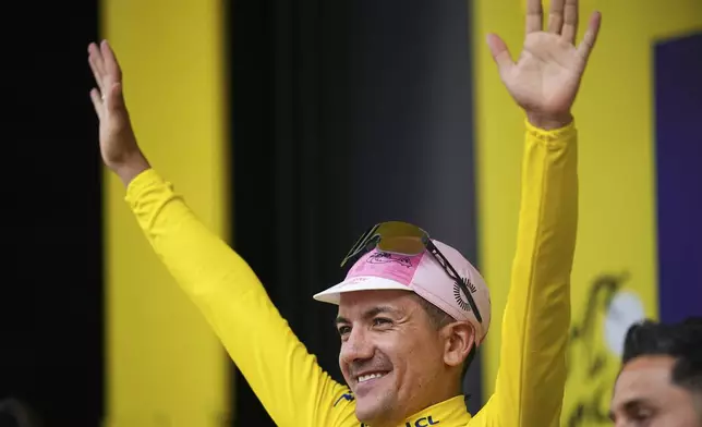 Ecuador's Richard Carapaz, wearing the overall leader's yellow jersey, celebrates on the podium after the third stage of the Tour de France cycling race over 230.8 kilometers (143.4 miles) with start in Piacenza and finish in Turin, Italy, Monday, July 1, 2024. (AP Photo/Daniel Cole)