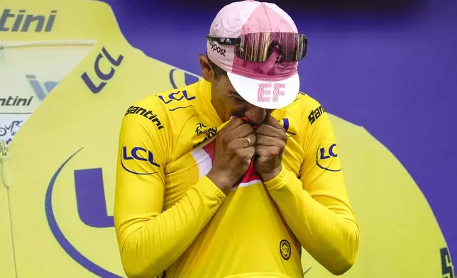 Ecuador's Richard Carapaz kisses the overall leader's yellow jersey on the podium after the third stage of the Tour de France cycling race over 230.8 kilometers (143.4 miles) with start in Piacenza and finish in Turin, Italy, Monday, July 1, 2024. (AP Photo/Jerome Delay)