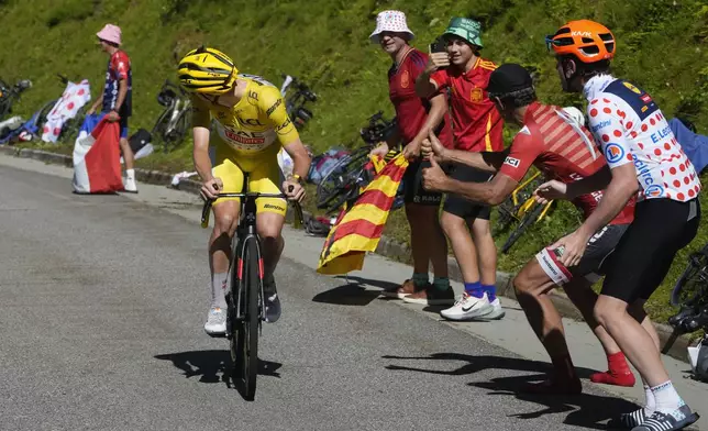 Stage winner Slovenia's Tadej Pogacar, wearing the overall leader's yellow jersey, turns around to see how much lead he has on his main rival Denmark's Jonas Vingegaard as he climbs towards Plateau de Beille during the fifteenth stage of the Tour de France cycling race over 198 kilometers (123 miles) with start in Loudenvielle and finish on Plateau de Beille, France, Sunday, July 14, 2024. (AP Photo/Jerome Delay)