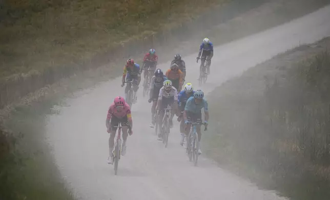 The breakaway group rides in the dust on a gravel road during the ninth stage of the Tour de France cycling race over 199 kilometers (123.7 miles) with start and finish in Troyes, France, Sunday, July 7, 2024. (AP Photo/Daniel Cole)