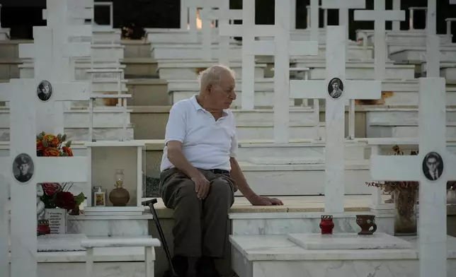 Loucas Alexandrou, 94, sits by the grave of his son Christakis Alexandrou, Alexandrides, who where killed on 22 of July 1974 during the Turkish invasion, at the military cemetery in the divided capital Nicosia, Cyprus, Friday, July 19, 2024. Saturday marks the 50th anniversary of Cyprus' ethnic division after Turkish invaded in the summer of 1974 in the wake of an Athens junta-backed coup aiming at union with Greece. (AP Photo/Petros Karadjias)