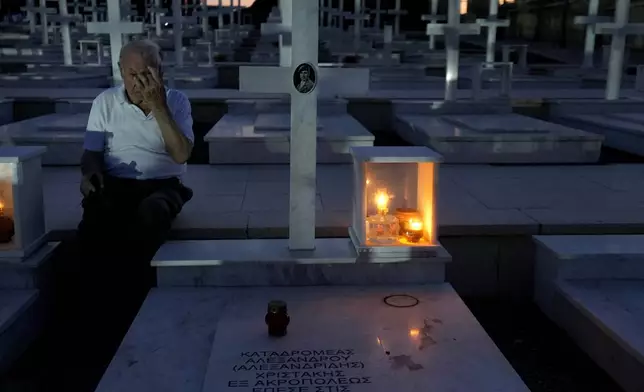 Loucas Alexandrou, 94, seats by the grave of his son Christakis Alexandrou, Alexandrides, who where killed on 22 of July 1974 during the Turkish invasion, at the military cemetery in the divided capital Nicosia, Cyprus, Friday, July 19, 2024. Saturday marks the 50th anniversary of Cyprus' ethnic division after Turkish invaded in the summer of 1974 in the wake of an Athens junta-backed coup aiming at union with Greece. (AP Photo/Petros Karadjias)