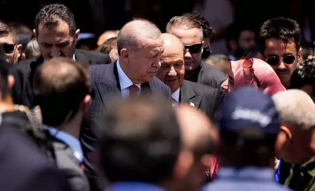 Turkish President Recep Tayyip Erdogan, center, and Cypriot leader Ersin Tatar, rear right, talk with a woman after the end of a military parade, in the Turkish occupied area of the divided capital Nicosia, Cyprus, Saturday, July 20, 2024. Today marks the 50th anniversary of Cyprus' ethnic division after Turkish invaded in the summer of 1974 in the wake of an Athens junta-backed coup aiming at union with Greece. (AP Photo/Petros Karadjias)