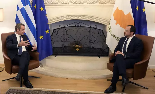 Cyprus' President Nikos Christodoulides, right, and Greek Prime Minister Kyriakos Mitsotakis talk during their meeting in the divided capital Nicosia, Cyprus, Saturday, July 20, 2024. Greek Cypriot commemorations include the unveiling of memorials to fallen heroes, church services and a gathering late Saturday at the Presidential Palace addressed — for the first time — by Greek Prime Minister Kyriakos Mitsotakis. (AP Photo/Petros Karadjias)