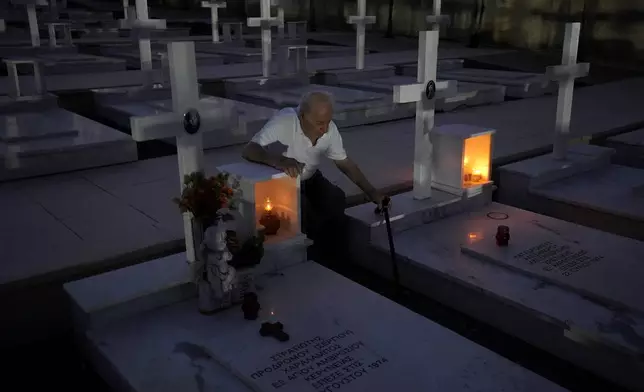 Loucas Alexandrou, 94, seats by the grave, right, of his son Christakis Alexandrou, Alexandrides, who where killed on 22 of July 1974 during the Turkish invasion, at the military cemetery in the divided capital Nicosia, Cyprus, Friday, July 19, 2024. Saturday marks the 50th anniversary of Cyprus' ethnic division after Turkish invaded in the summer of 1974 in the wake of an Athens junta-backed coup aiming at union with Greece. (AP Photo/Petros Karadjias)