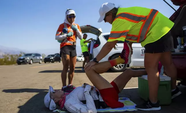 Karla Kent stretches during a brief pause along California Route 190 during the Badwater 135 mile (217 kilometer) ultramarathon in Death Valley, Calif., Tuesday, July 23, 2024. (AP Photo/Ty ONeil)