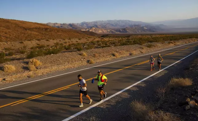 Runners start uphill at sunrise on California Route 190 during the Badwater 135 mile (217 kilometer) ultramarathon in Death Valley, Calif., Tuesday, July 23, 2024. (AP Photo/Ty ONeil)