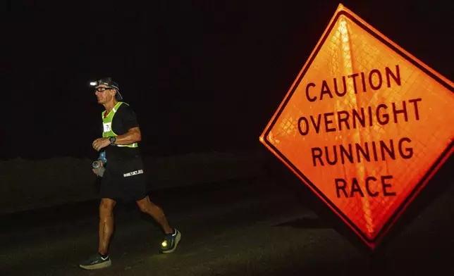 A runner passes by a sign warning traffic of the race on Route 66 during the Badwater 135 mile (217 kilometer) ultramarathon in Death Valley, Calif., Monday, July 22, 2024. (AP Photo/Ty ONeil)