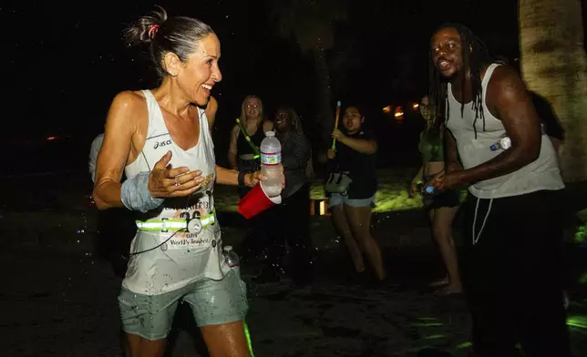 The self proclaimed "Death Valley cheerleaders" cheer and spray water at runner Caryn Lubetsky, from Miami Shores, Fla., on California Route 190 during the Badwater 135 mile (217 kilometer) ultramarathon in Death Valley, Calif., Tuesday, July 23, 2024. (AP Photo/Ty ONeil)