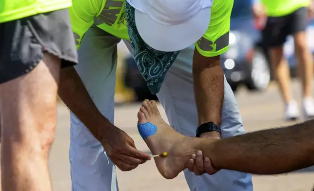 A crew member looks after a runners feet in alongside California Route 190 during the Badwater 135 mile (217 kilometer) ultramarathon in Death Valley, Calif., Tuesday, July 23, 2024. (AP Photo/Ty ONeil)