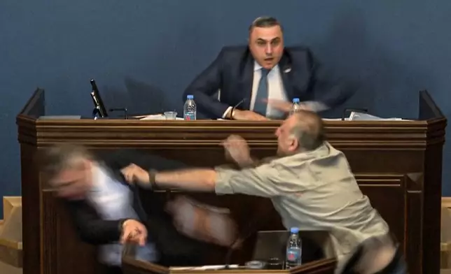 FILE This photo taken from video released by Georgian Parliament on April 15, 2024, shows the leader of the ruling Georgian Dream party's group in parliament, Mamuka Mdinaradze, left, being punched in the face by opposition MP Alexander Elisashvili while speaking in Tbilisi, Georgia. The scuffle came as parliament debated the bill on foreign influence that became law in early June. As it made its way through parliament, it sparked mass protests by those opposing it. Critics compared it to similar legislation Russia uses to stifle dissent and they worried it would jeopardize Georgia's prospects of joining the European Union. (Georgian Parliament via AP, File)